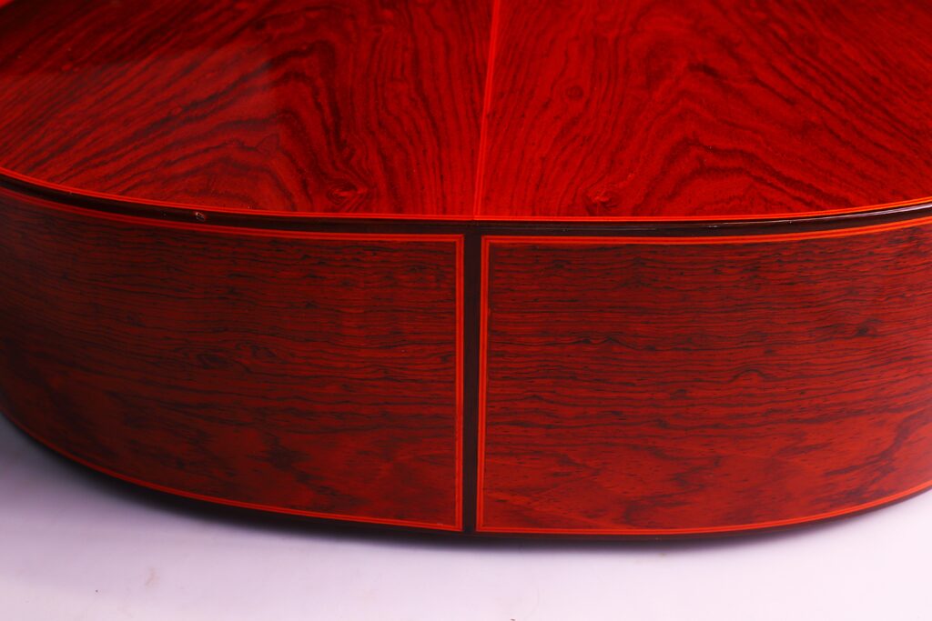 Nahaufnahme Einer Hermanos Conde 1991 Paco De Lucia Special Flamenco Gitarre Mit Glänzendem, Rötlich-Braunem Holz Mit Sichtbarer Maserung Und Dunklen Einlegearbeiten. Die Reflektierende Oberfläche Betont Die Feine Handwerkskunst Und Die Elegante Textur Der Gitarre.