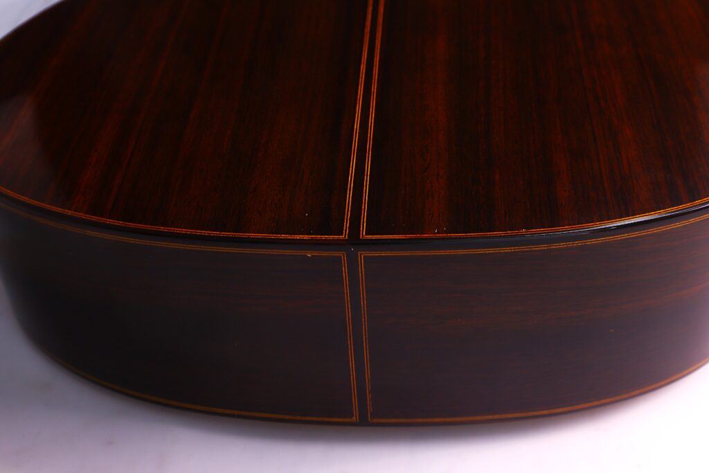 Nahaufnahme Der Rückseite Und Der Seite Einer Luis Sanchez 2011 Negra Flamenco Gitarre, Gefertigt Aus Dunklem, Poliertem Holz Mit Sichtbarer Maserung Und Feinen Einlegearbeiten, Fotografiert Vor Einem Hellen Hintergrund.