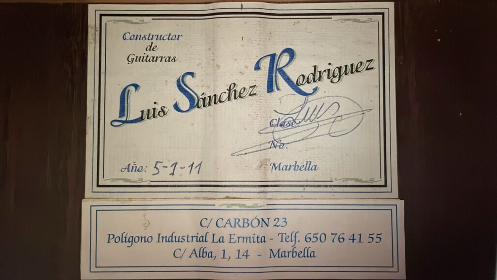 Ein Etikett Für Die Luis Sanchez 2011 Negra Flamenco Gitarre Enthält Handgeschriebenen Und Gedruckten Text, Kontaktinformationen, Adressen In Marbella (Spanien), Eine Blaue Dekorative Umrandung Und Ist Mit Dem Datum 5-1-11 Versehen.