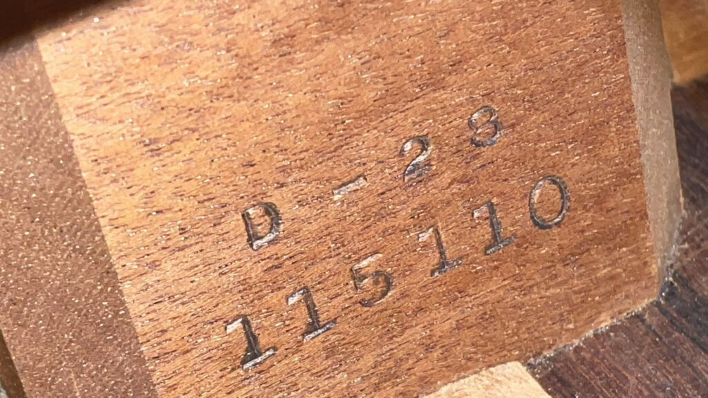 Nahaufnahme Einer Martin D-28 1950 Akustik Gitarre, Die „D-28“ Über Der Seriennummer „115110“ Gestempelt Zeigt, Beide In Die Holzoberfläche Gepresst.