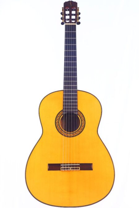 The Alberto Pantoja 2023 Negra Flamenco Guitar, featuring a light wood body, dark fretboard, and ornate rosette, stands upright against a plain white background.