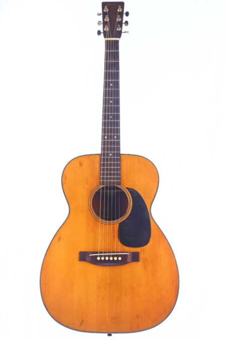 The Martin 00-18 1946 Acoustic Guitar features a light brown wooden body, dark fretboard, six tuning pegs, black pickguard, and visible wear, shown against a white background.