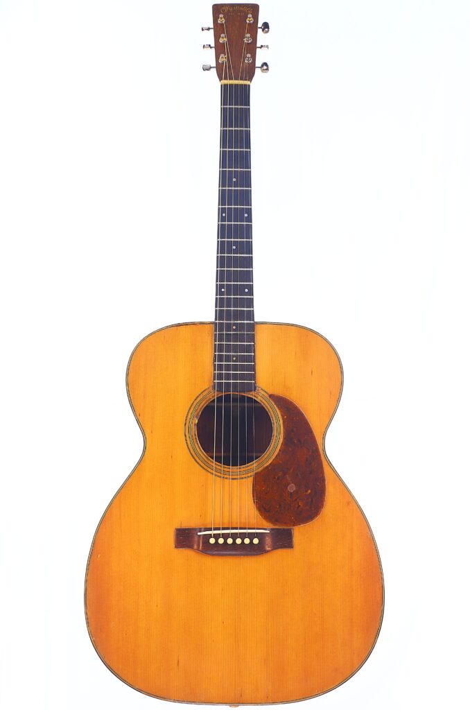 The Martin 000-21 1947 Acoustic Guitar Features A Natural Wood Finish, Six Strings, A Dark Pickguard, And A Simple Design, Displayed Against A Plain White Background.