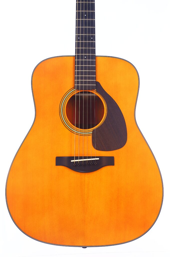 A Close-Up Of The Yamaha Fg5 Acoustic Guitar, Featuring A Light Orange-Brown Body, Dark Pickguard, And Six Strings, Photographed Against A White Background.