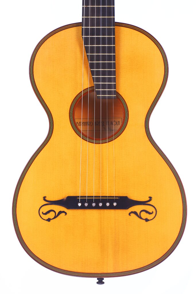 A Close-Up Of The Bernhard Kresse 2011 Stauffer Romantic Guitar’s Body, Featuring Six Strings, A Light Wood Finish, Black Decorative Designs On The Lower Part, And Part Of The Neck With Visible Frets.