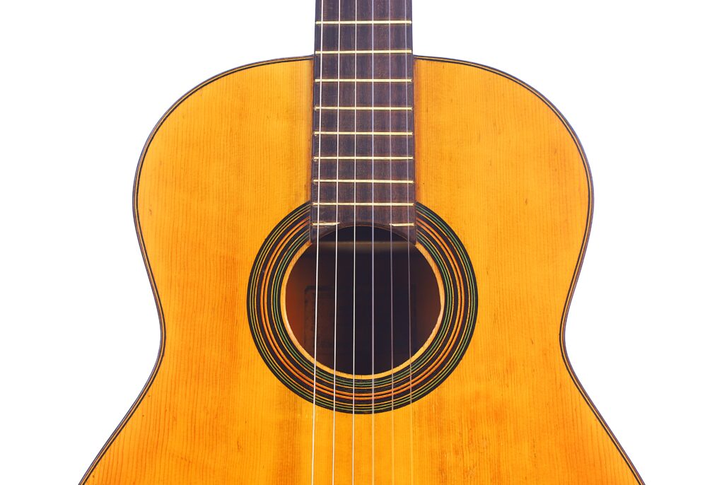 Grande plano da guitarra clássica Domingo Esteso 1934, destacando o corpo, a caixa de ressonância, as cordas e parte da escala contra um fundo branco.