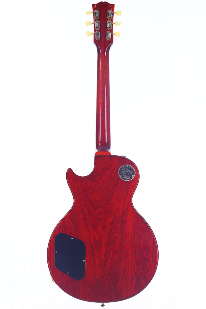 Rear View Of A Red Gibson Les Paul 1960 60Th Vos Anniversary Electric Guitar With A Wooden Finish, Showing The Back Of The Body, Neck, Tuning Pegs, Two Access Panels, And A Round Label On The Body.