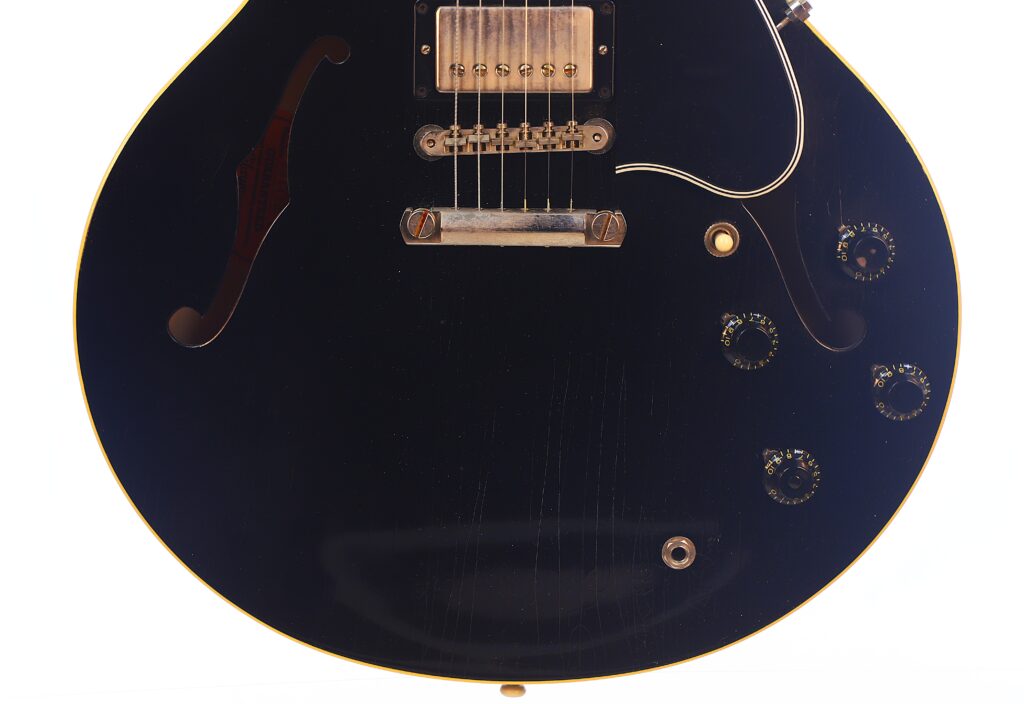 Nahaufnahme Der Unteren Hälfte Einer Gibson Es-335 Td Murphy Lab E-Gitarre, Die Ihren Schwarzen Semi-Hollow-Korpus, Steg, Tonabnehmer, Regler Und F-Loch Vor Weißem Hintergrund Zeigt.