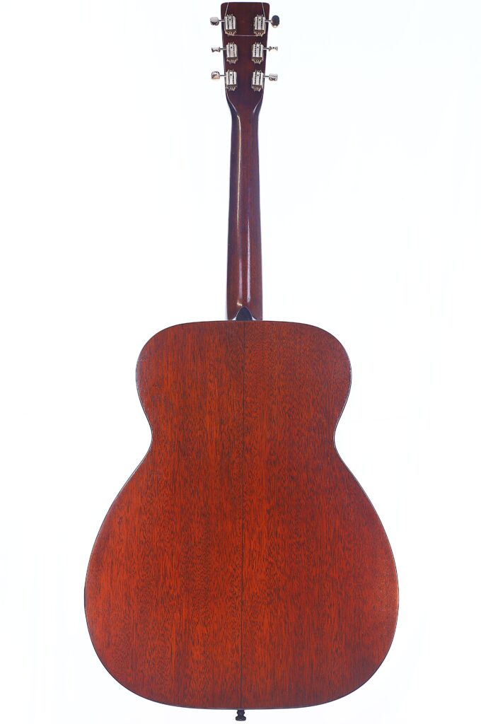 A Rear View Of The Martin 00-18 1946 Acoustic Guitar Shows Its Reddish-Brown Wooden Body With Visible Grain, And A Dark Brown Neck And Headstock, All Set Against A White Background.