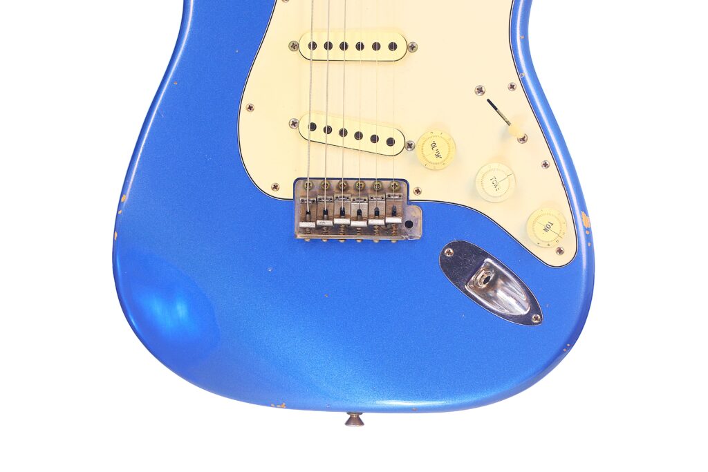 Eine Nahaufnahme Der Fender Stratocaster 1960 Relic Cunetto/Cruz E-Gitarre Zeigt Ihren Blauen Korpus, Das Cremefarbene Schlagbrett, Drei Regler, Einen Tonabnehmerwahlschalter Sowie Sichtbare Kratzer Und Abnutzungsspuren.