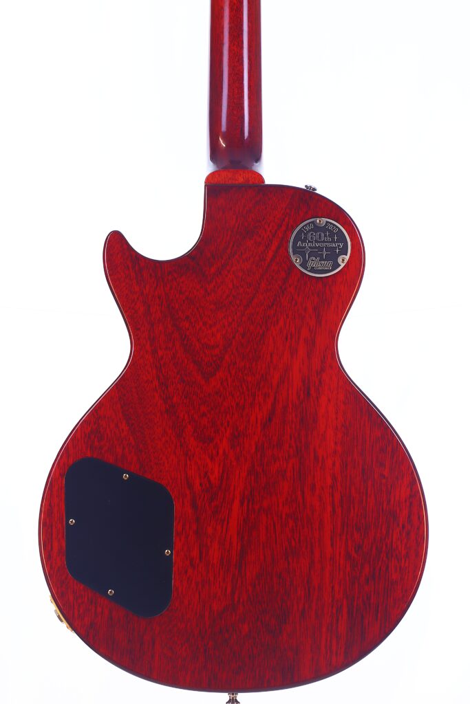 The Back Of A Gibson Les Paul 1960 60Th Vos Anniversary Electric Guitar Displays Red Wood Grain, Two Black Access Panels, And A Metal “Gibson” Label Near The Neck Joint, Shown Against A White Background.