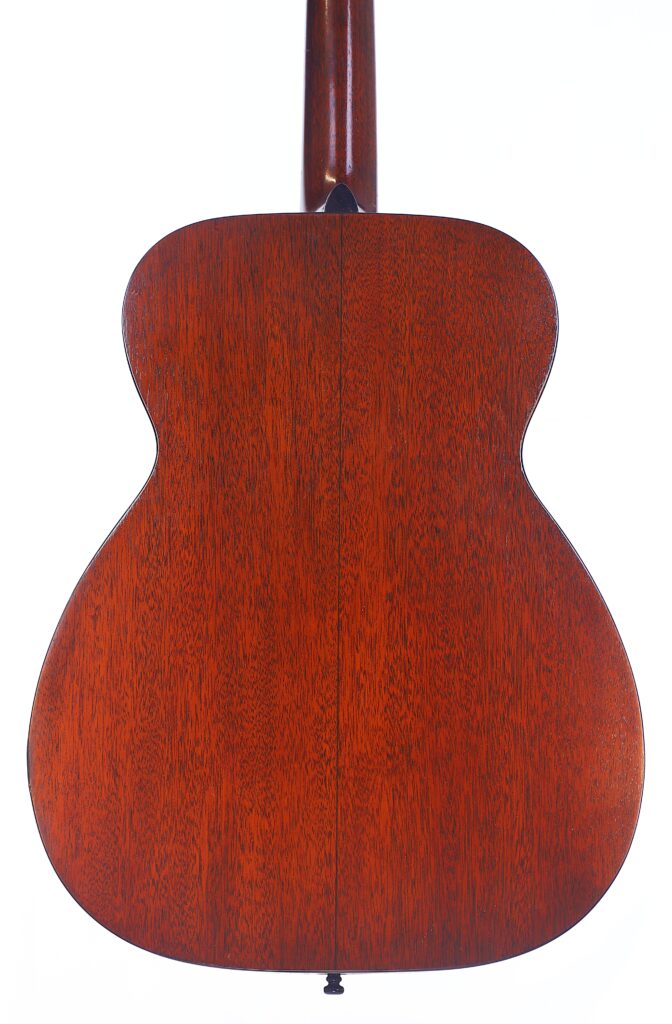 The Image Shows The Back Of A Martin 00-18 1946 Acoustic Guitar With A Rich, Reddish-Brown Wood Finish, A Visible Central Seam Running Vertically Through The Body, And Clearly Visible Wood Grain.