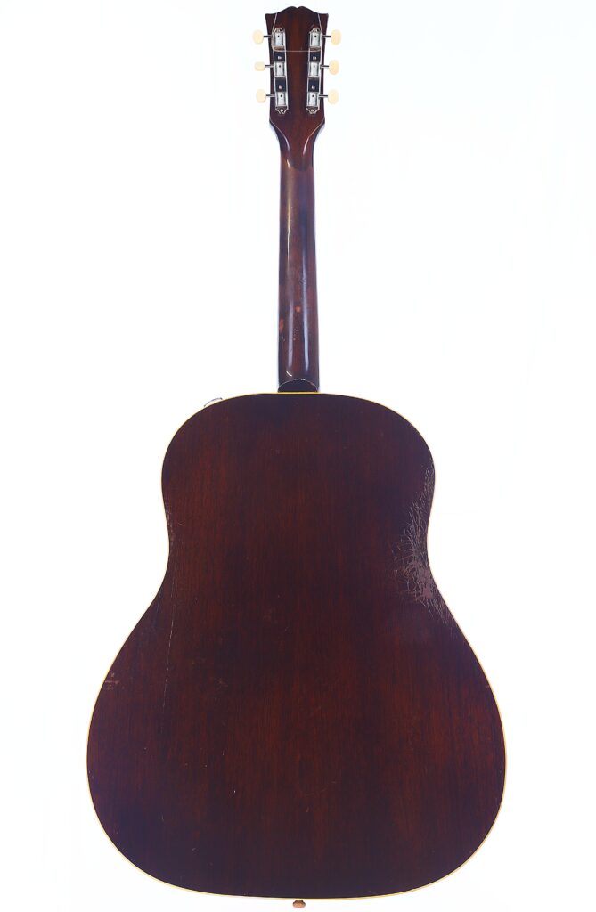 A Rear View Of The Gibson J-45 1957 Acoustic Guitar With A Dark Wooden Finish, Displaying The Back Of Its Body, Neck, And Headstock Against A White Background.