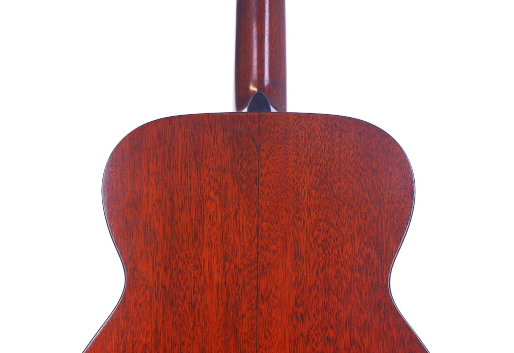 Close-Up Of The Back Of A Martin 00-18 1946 Acoustic Guitar, Showing Polished Reddish-Brown Wood Grain With A Vertical Center Seam And The Neck Visible At The Top, Set Against A White Background.