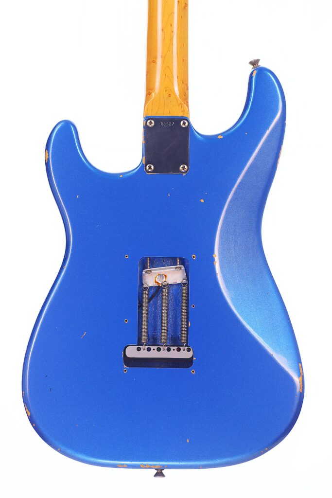 Die Rückseite Einer Blauen Fender Stratocaster 1960 Relic Cunetto/Cruz E-Gitarre Mit Ahornhals, Metallhalsplatte Und Abgenutzten, Abgesplitterten Stellen Am Korpus Ist Vor Einem Weißen Hintergrund Fotografiert.