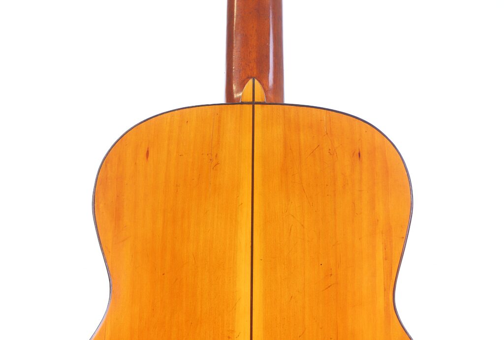 Grande plano do fundo de uma guitarra clássica Domingo Esteso 1934 com uma superfície de madeira que mostra uma costura vertical no centro e um grão de madeira visível.