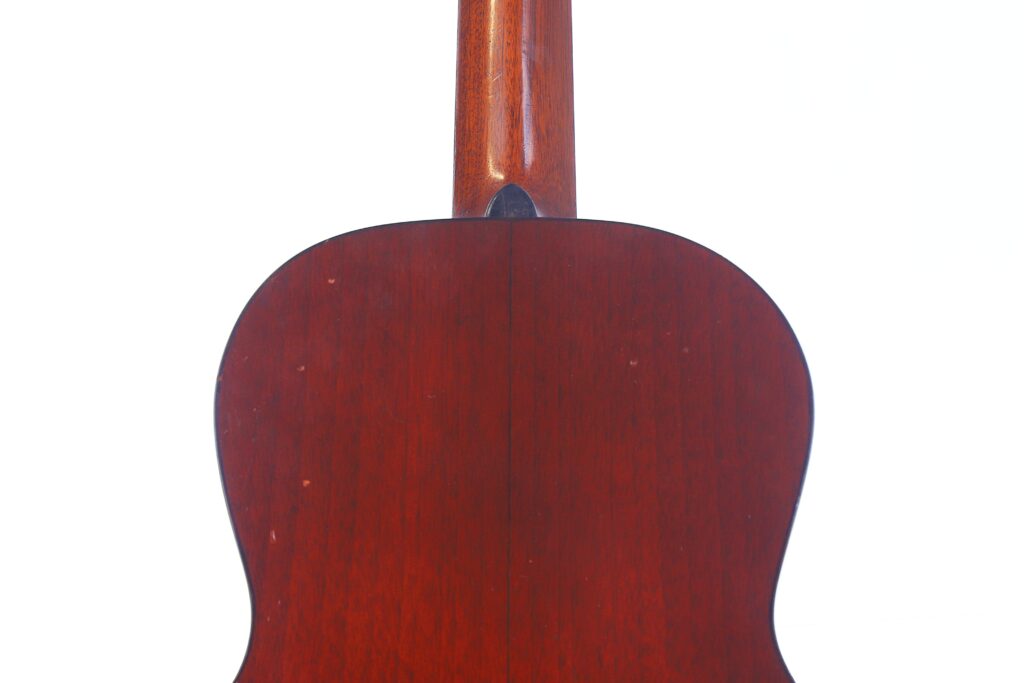 Close-Up View Of The Back Of A Martin 0-18 1926 Acoustic Guitar, Highlighting The Wooden Body And Neck With A Rich Brown Finish And Visible Central Seam, Set Against A White Background.