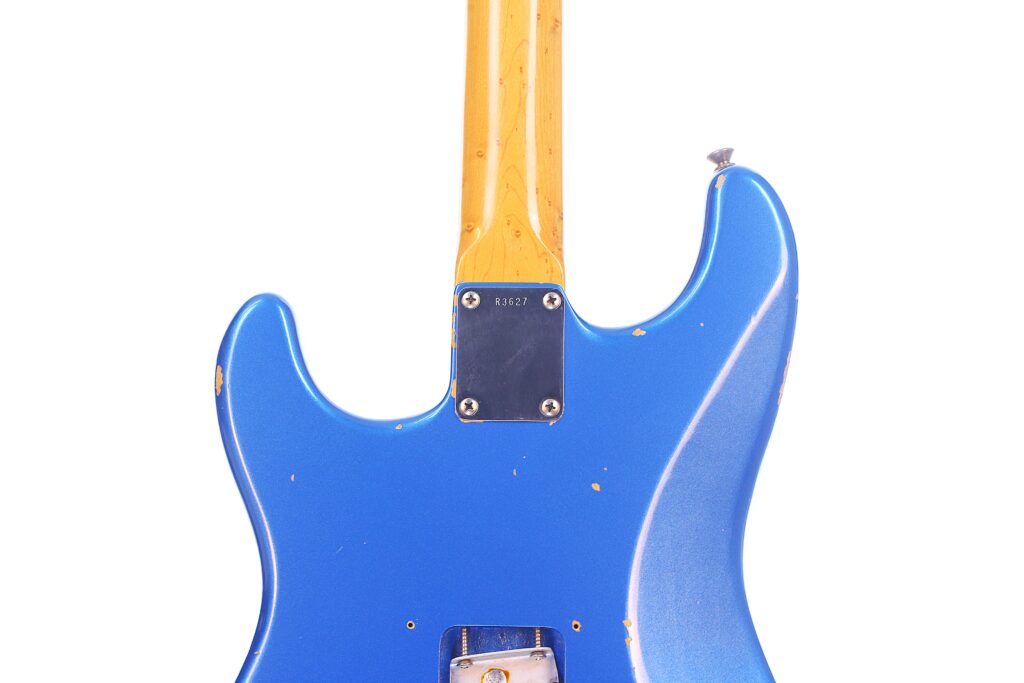 Eine Nahaufnahme Der Rückseite Einer Blauen Fender Stratocaster 1960 Relic Cunetto/Cruz E-Gitarre Mit Gelbem Hals, Die Kratzer Und Dellen Vor Einem Weißen Hintergrund Zeigt.