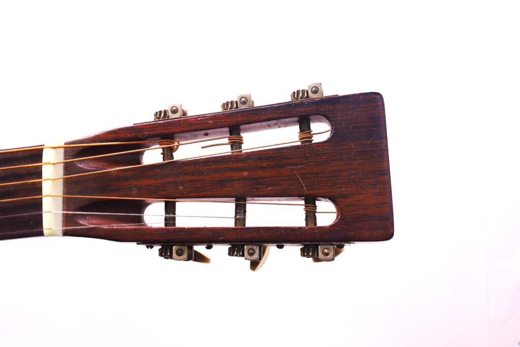 Close-Up Of The Headstock Of A Martin 0-18 1926 Acoustic Guitar Showing Tuning Pegs And Strings Against A White Background.
