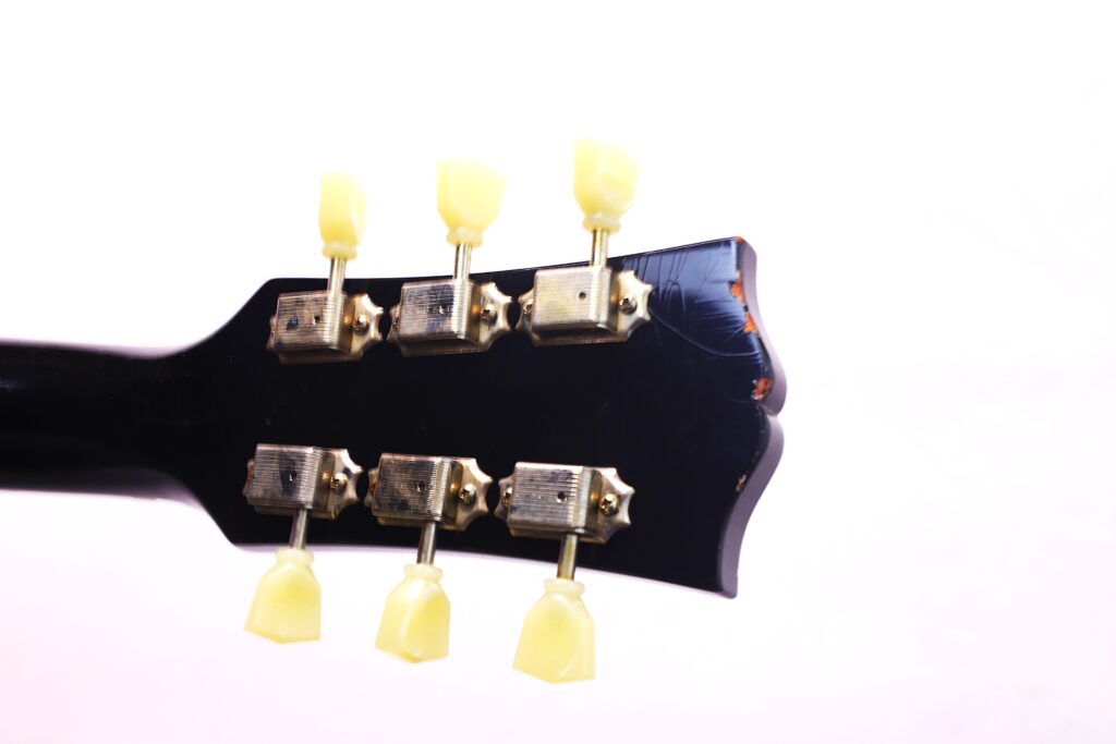 Nahaufnahme Der Rückseite Der Kopfplatte Einer Gibson Es-335 Td Murphy Lab E-Gitarre Mit Sechs Stimmwirbeln Mit Cremefarbenen Knöpfen Und Sichtbaren Kratzern Auf Dem Dunklen Holz.