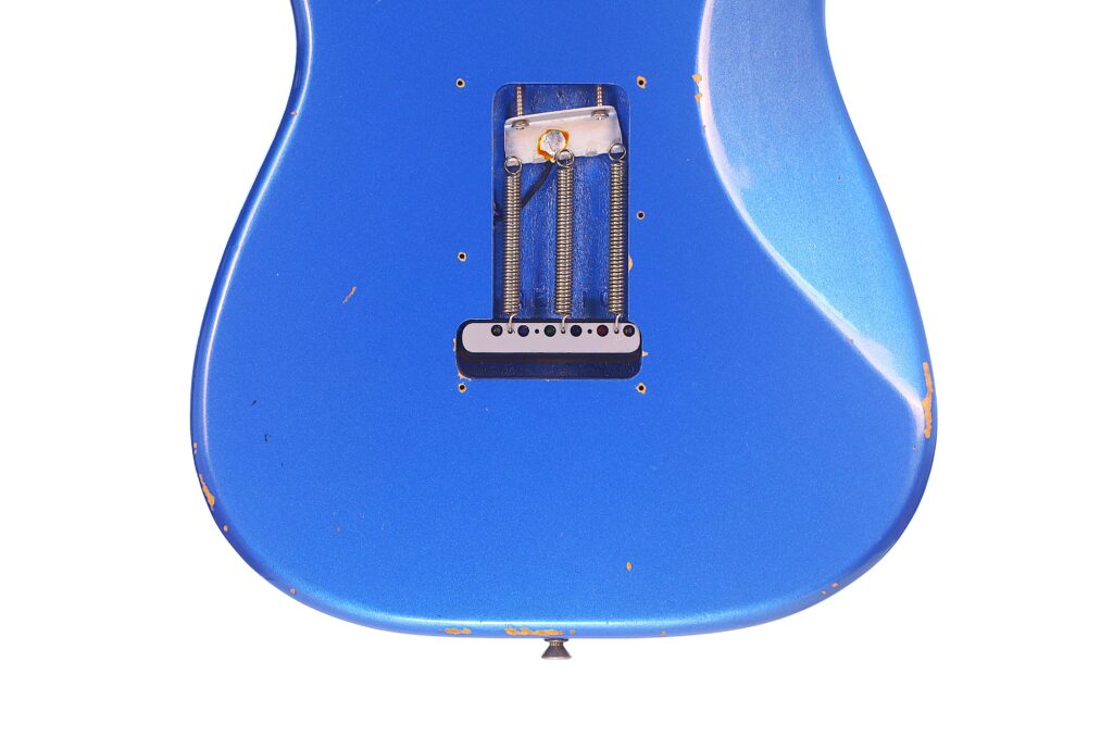 Nahaufnahme Der Rückseite Einer Blauen Fender Stratocaster 1960 Relic Cunetto/Cruz E-Gitarre Mit Freiliegenden Internen Federn Und Abgenutzten Kanten Mit Kleineren Kratzern. Die Gitarre Ist Vor Einem Weißen Hintergrund Platziert.