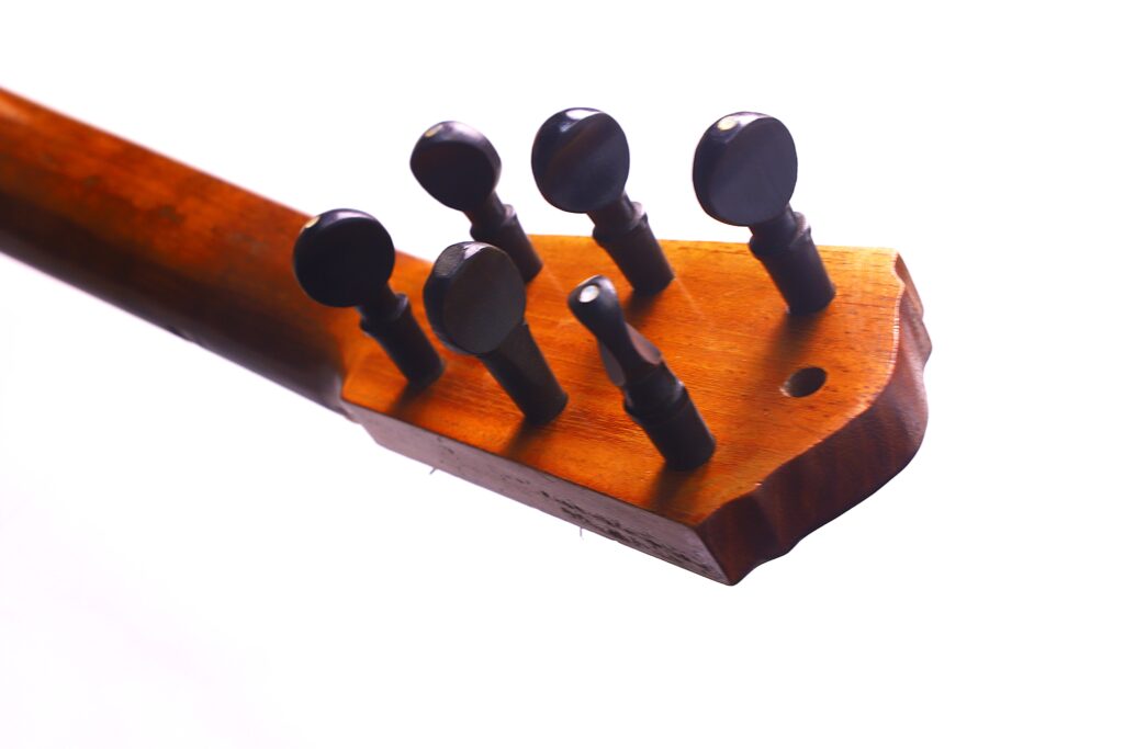 Grande plano do cabeçote de madeira de uma guitarra clássica Domingo Esteso 1934, com seis cravelhas de afinação pretas sobre um fundo branco.