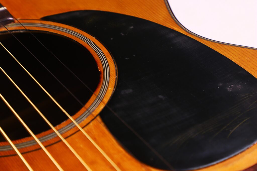 Close-Up Of A Martin 00-18 1946 Acoustic Guitar Featuring Its Sound Hole, Strings, And Black Pickguard On A Wooden Body.