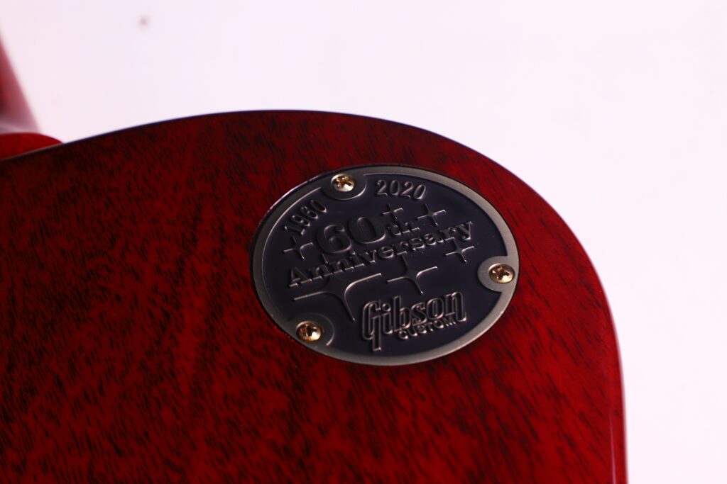 Close-Up Of A Metal Plate With &Quot;1960-2020, 60Th Anniversary, Gibson&Quot; Engraved, Attached By Four Screws To The Red Wooden Body Of The Gibson Les Paul 1960 60Th Vos Anniversary Electric Guitar.