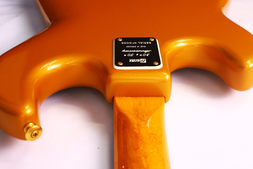 Close-Up Of The Back Of A Burns Legend 1994 Electric Guitar, Highlighting The Neck Joint Where A Metal Plate Displaying The Serial Number And Branding Is Secured With Four Screws.
