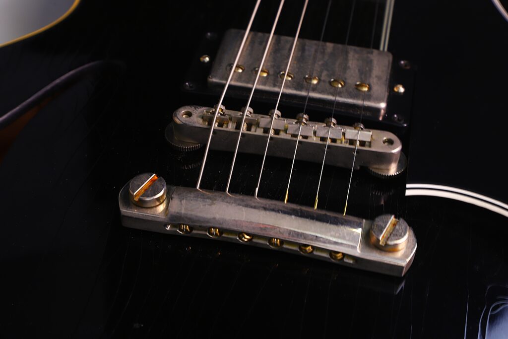 Nahaufnahme Einer Gibson Es-335 Td Murphy Lab E-Gitarre, Die Die Schwarze Lackierung, Den Metallsteg, Die Saiten Und Die Tonabnehmer Mit Detaillierten Reflexionen Und Texturen Auf Der Hardware Hervorhebt.