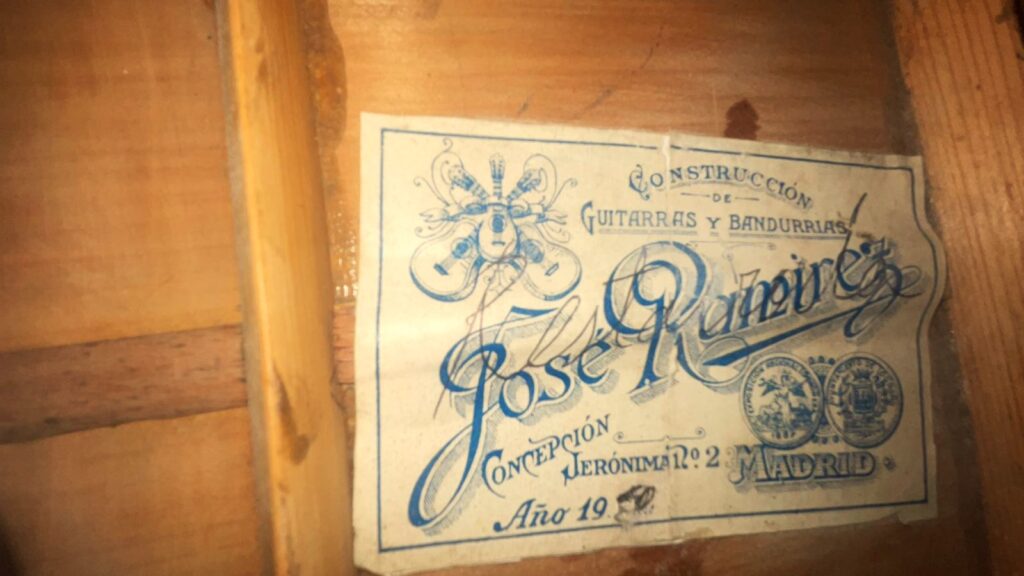 Grande plano da etiqueta vintage no interior de uma guitarra clássica Domingo Esteso 1934 com a etiqueta „Construccion De Guitarras Y Bandurrias, José Ramirez, Concepción Jeronima 2, Madrid, Año 19--“ Com ilustrações decorativas a azul.