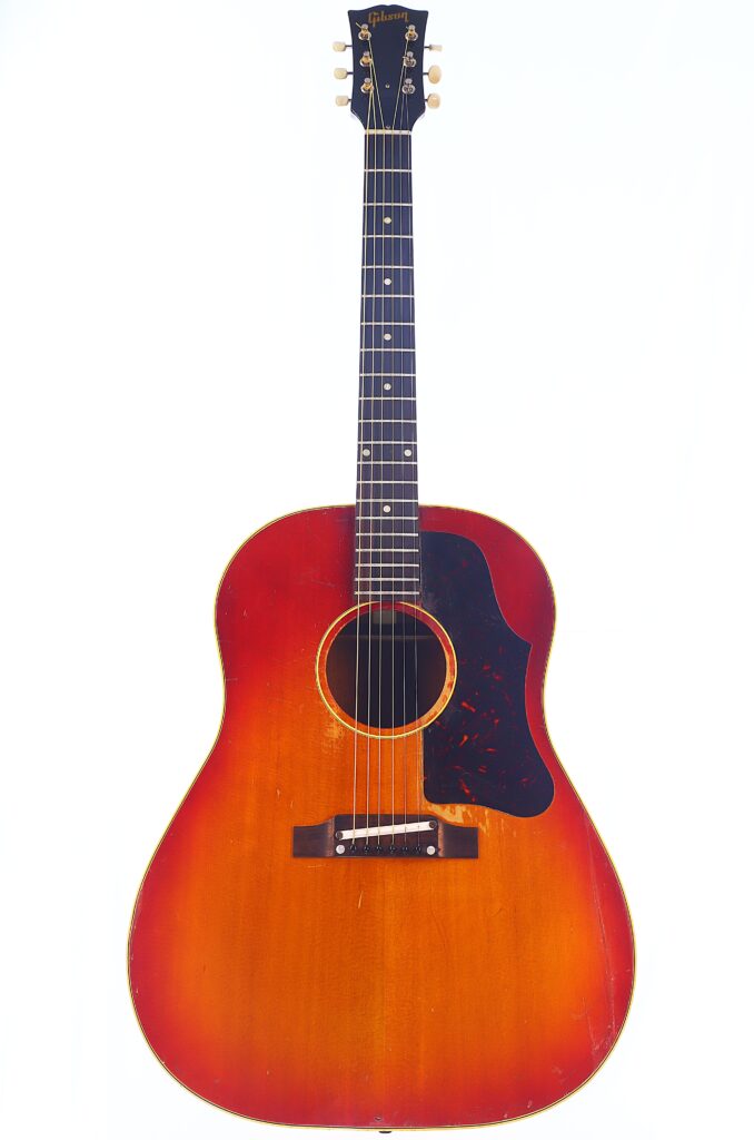 Eine Gibson J-45 1962 Akustik Gitarre Mit Sunburst-Lackierung, Dunklem Schlagbrett, Sechs Stimmwirbeln Und &Quot;Gibson&Quot;-Logo Auf Der Kopfplatte, Fotografiert Vor Einem Schlichten Weißen Hintergrund.