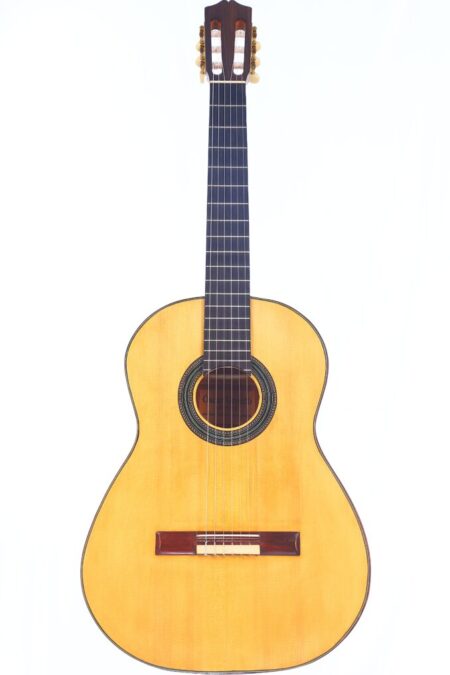 The Oscar Orozco 2023 Santos Hernández Flamenco Guitar Features A Light Wooden Body, Dark Fretboard, And Six Strings, Shown Upright Against A Plain White Background.