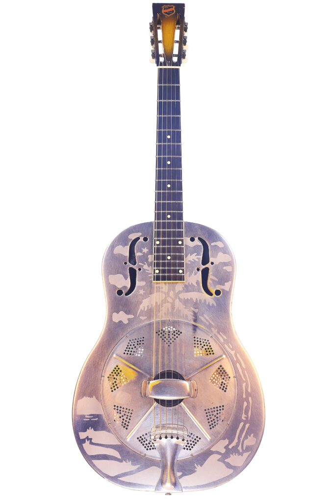 Die National Reso-Phonic Style O 2009 Akustik Gitarre Ist Eine Resonatorgitarre Mit Metallkorpus, Polierter Silberlackierung, F-Förmigen Schalllöchern, Dekorativer Gravur, Rundem Hals Und Markantem Resonatorkonus.