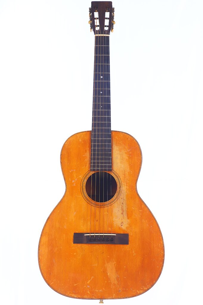 Eine Martin 0-18 1926 Akustik Gitarre Mit Naturholz-Finish, Dunklem Holzgriffbrett, Sechs Saiten Und Sichtbaren Gebrauchsspuren Am Korpus, Abgebildet Auf Weißem Hintergrund.