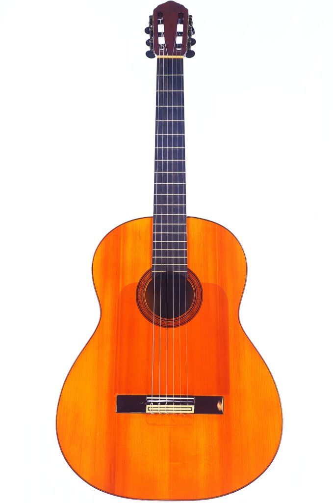 Die Manuel Reyes 1955 Flamenco Gitarre Ist Eine Klassische Akustikgitarre Mit Sechs Saiten, Einer Natürlichen Holzoberfläche, Einem Dunklen Griffbrett Und Einem Runden Schallloch Auf Weißem Hintergrund.