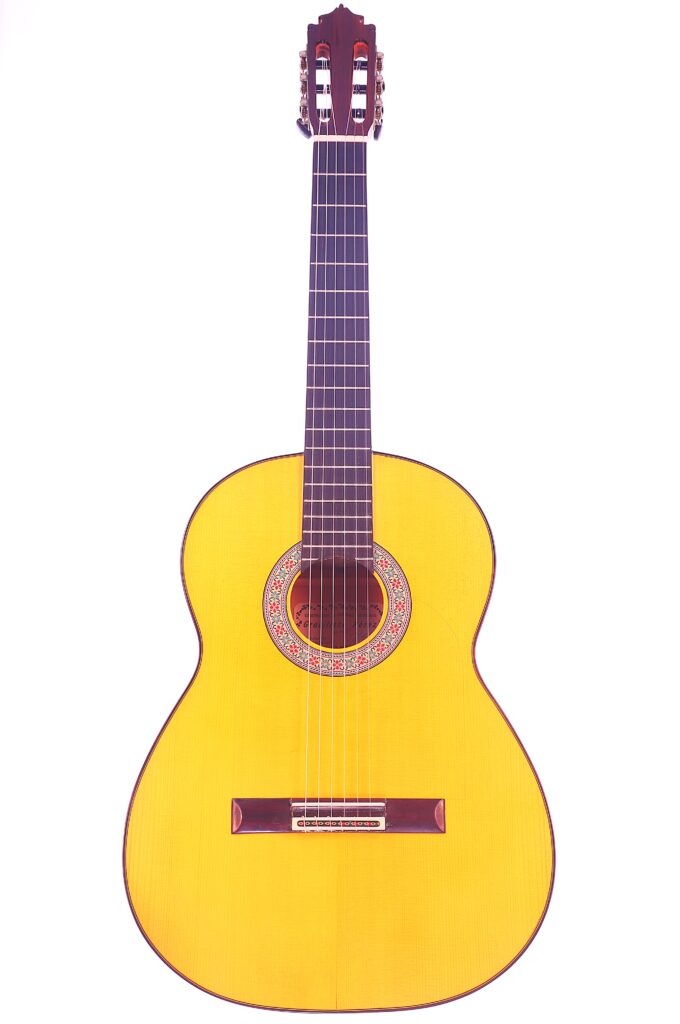 Die Graciliano Perez 2025 Flamenco Gitarre Hat Einen Hellen Holzkorpus, Ein Dunkles Griffbrett Und Eine Dekorative Rosette Um Das Schallloch, Die Auf Einem Weißen Hintergrund Abgebildet Ist.