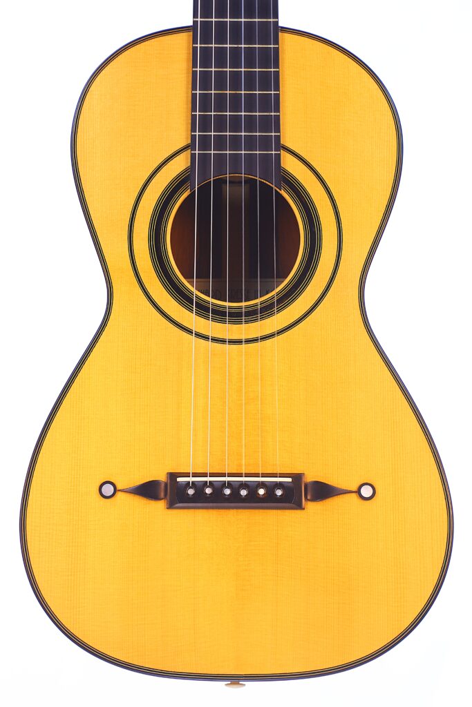 천연 목재 마감, 6개의 현, 흰색 배경에 장식용 검은색 바인딩이 있는 클래식 어쿠스틱 기타, 베른하르트 크레세 1999 파노르모 로맨틱 기타의 몸통과 하부 목을 클로즈업한 사진입니다.