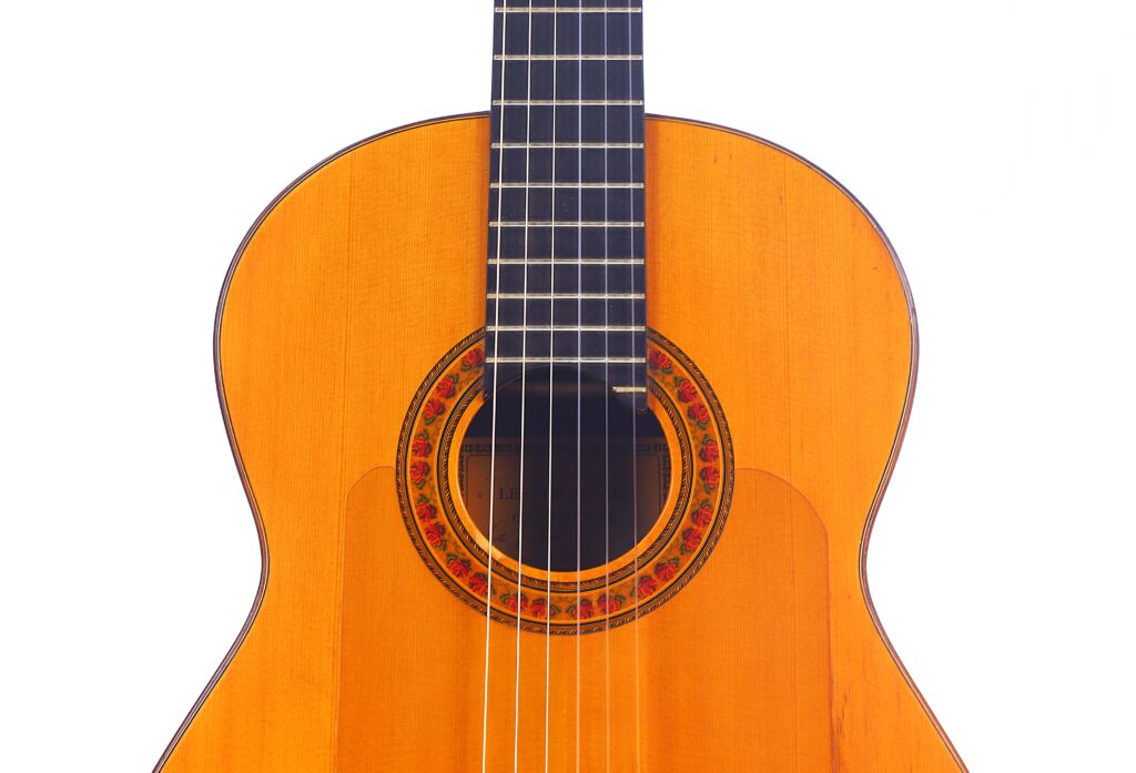 Eine Nahaufnahme Des Korpus Und Des Halses Einer Lester Devoe 1996 Negra Flamenco-Gitarre Mit Holzoberfläche, Die Das Schallloch, Die Rosette Und Die Saiten Vor Einem Weißen Hintergrund Zeigt.