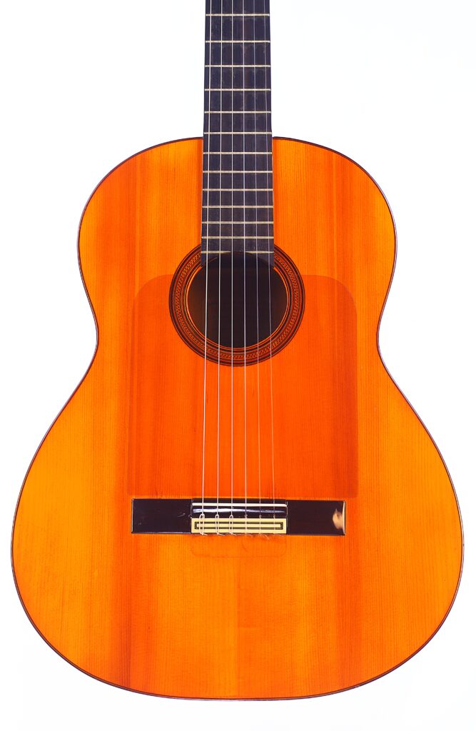 Die Manuel Reyes 1955 Flamenco-Gitarre Hat Einen Leuchtend Orange-Braunen Holzkorpus, Sechs Saiten, Einen Schwarzen Steg Und Eine Detaillierte Kreisförmige Rosette Um Das Schallloch, Fotografiert Auf Weißem Hintergrund.