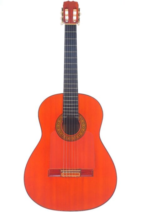 Die Hermanos Conde 1983 Faustino Conde Flamenco Gitarre Ist Eine Klassische Akustikgitarre Mit Einem Rötlich-Braunen Holzkorpus, Sechs Saiten, Einem Dunklen Griffbrett Und Einem Verzierten Schallloch, Das Aufrecht Vor Einem Weißen Hintergrund Abgebildet Ist. Die Hermanos Conde 1983 Faustino Conde Flamenco Gitarre Ist Eine Klassische Akustikgitarre Mit Einem Rötlich-Braunen Holzkorpus, Sechs Saiten, Einem Dunklen Griffbrett Und Einem Verzierten Schallloch, Das Aufrecht Vor Einem Weißen Hintergrund Abgebildet Ist.