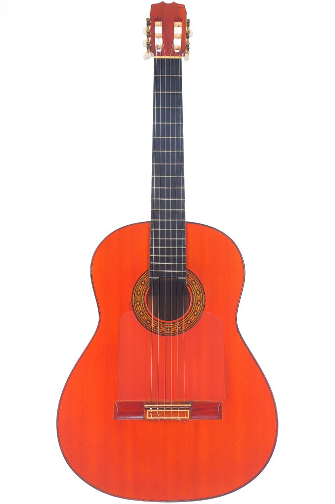 Die Hermanos Conde 1983 Faustino Conde Flamenco Gitarre Ist Eine Klassische Akustikgitarre Mit Einem Rötlich-Braunen Holzkorpus, Sechs Saiten, Einem Dunklen Griffbrett Und Einem Verzierten Schallloch, Das Aufrecht Vor Einem Weißen Hintergrund Abgebildet Ist.