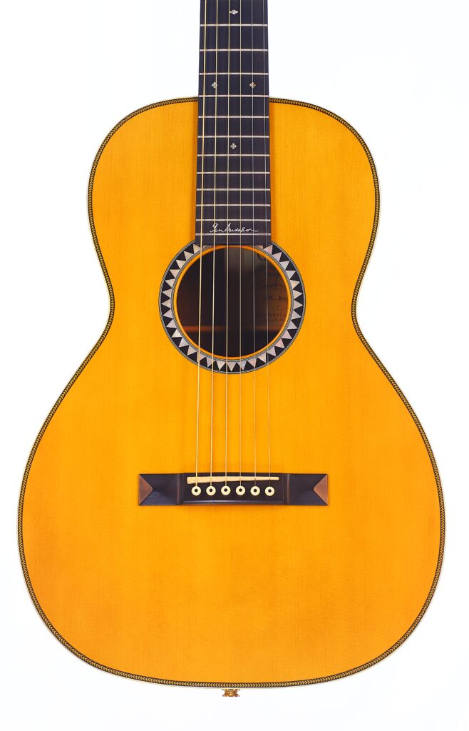 Die Martin 0-28 Ian Anderson Akustik Gitarre Hat Ein Helles Holzfinish, Sechs Saiten, Ein Verziertes Schallloch Und Markante Einlagen Auf Dem Steg Und Dem Griffbrett, Die Vor Einem Weißen Hintergrund Abgebildet Sind.