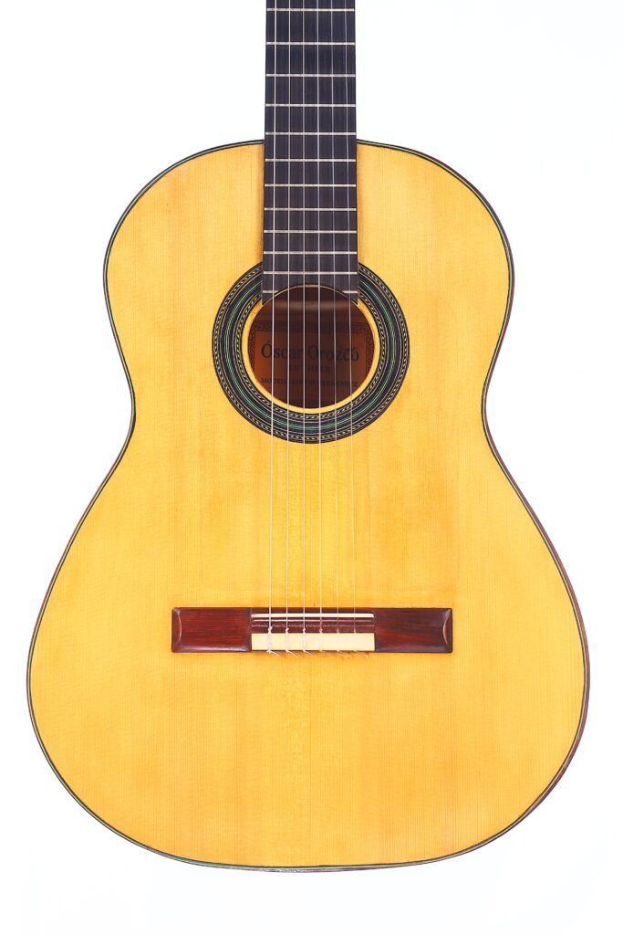 Die Oscar Orozco 2023 Santos Hernández Flamenco-Gitarre Ist Von Vorne Vor Einem Weißen Hintergrund Abgebildet. Zu Sehen Sind Der Korpus, Das Schallloch Mit Zierrosette, Der Steg Und Ein Teil Des Halses Mit Saiten.