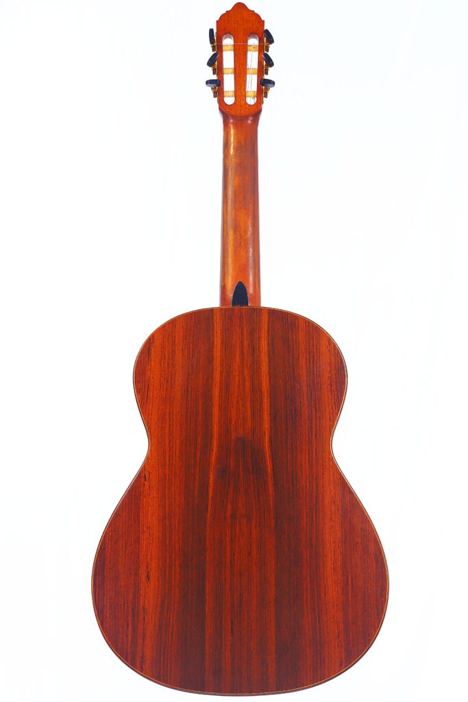 Das Bild Zeigt Die Rückansicht Einer Lester Devoe 1996 Negra Flamenco-Gitarre, Die Eine Glatte, Polierte Holzoberfläche Mit Sichtbarer Maserung Vor Einem Schlichten Weißen Hintergrund Aufweist.