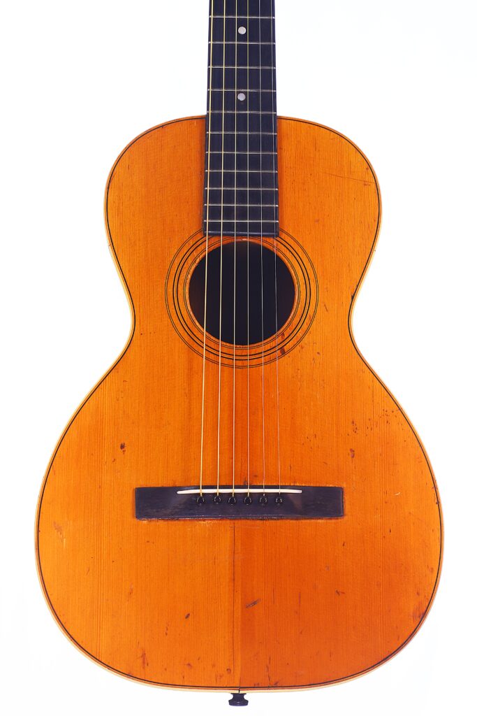 Die Washburn 1894 Parlor Akustik Gitarre Hat Einen Hellbraunen Holzkorpus, Sechs Saiten, Ein Rundes Schallloch Und Einen Dunklen Steg, Der Vor Einem Schlichten Weißen Hintergrund Steht.