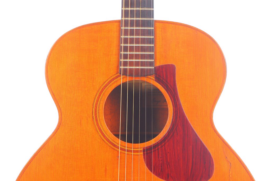 Nahaufnahme Von Korpus Und Hals Der Lowden F-9 1980 Akustik Gitarre Mit Sechs Saiten, Rundem Schallloch, Gepunktetem Schlagbrett Und Holzmaserung Auf Weißem Hintergrund.