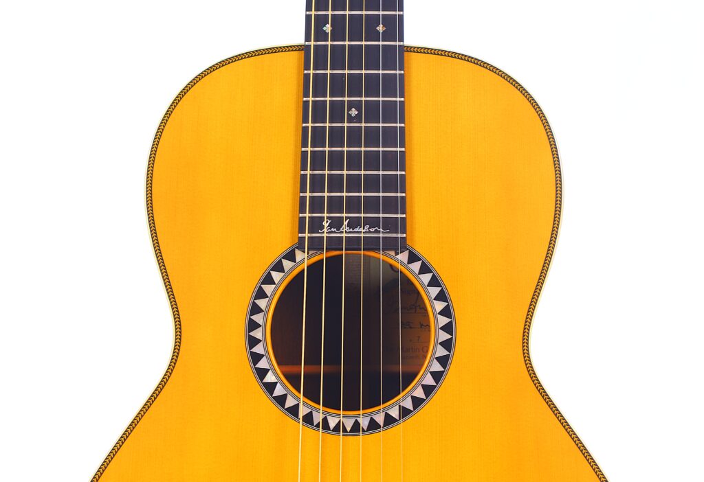 Nahaufnahme Der Martin 0-28 Ian Anderson Akustik Gitarre Mit Hellem Holzfinish, Schwarz-Weißer Rosette Und Sichtbaren Bünden Und Saiten Vor Weißem Hintergrund.