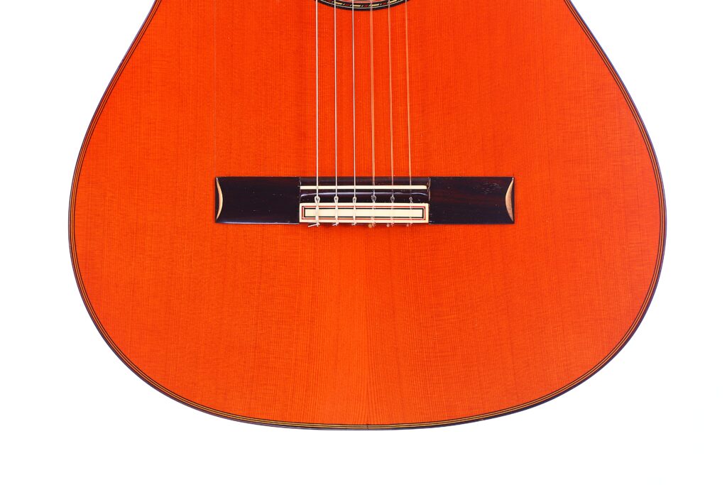 Nahaufnahme Der Hermanos Conde 1990 Paco De Lucia Special Flamenco Gitarre. Hervorzuheben Sind Die Saiten, Der Steg Und Die Rötlich Polierte Holzoberfläche In Der Unteren Hälfte Des Instruments.