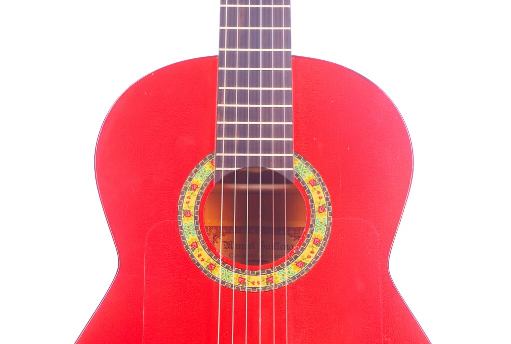 Nahaufnahme Einer Manuel Guillena 2017 Blanca Flamenco-Gitarre, Mit Den Saiten, Der Bunten Rosette Um Das Schallloch Und Einem Teil Des Halses, Alles Vor Einem Weißen Hintergrund.